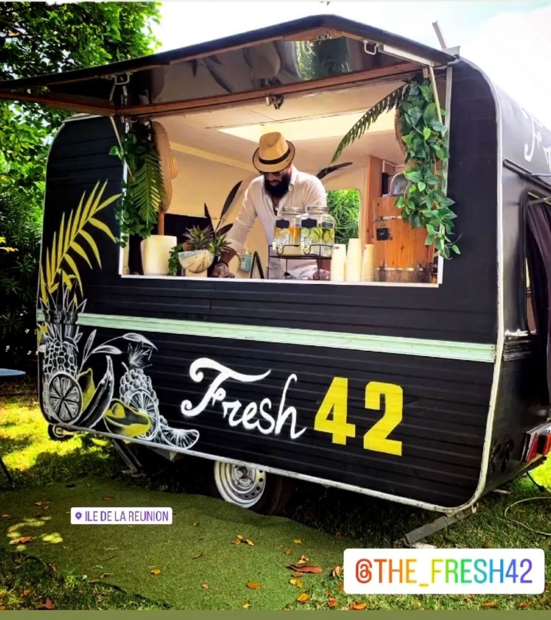 Man making drinks in a tropical-themed food truck labeled Fresh 42.